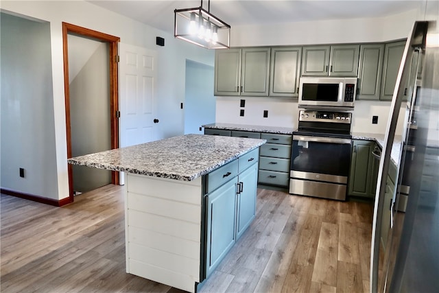 kitchen with stainless steel appliances, decorative light fixtures, light wood-type flooring, and a kitchen island