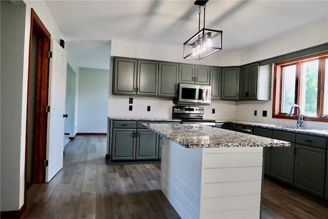 kitchen featuring a center island, dark wood-type flooring, stainless steel appliances, and hanging light fixtures