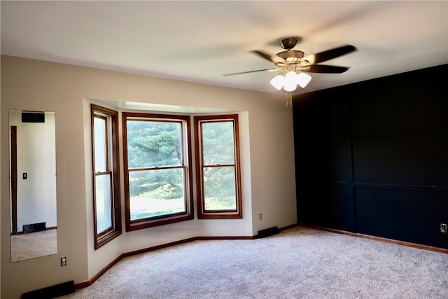 carpeted spare room with ceiling fan