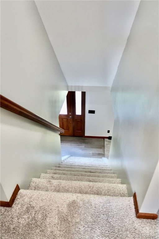 stairway featuring lofted ceiling and wood-type flooring