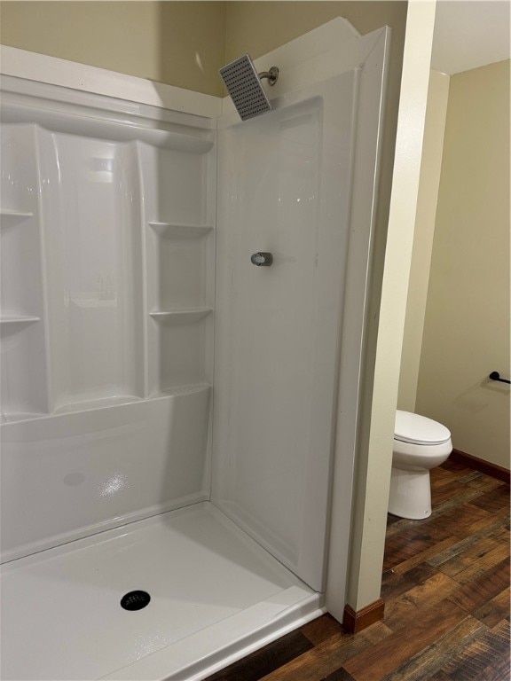 bathroom featuring toilet, hardwood / wood-style flooring, and a shower