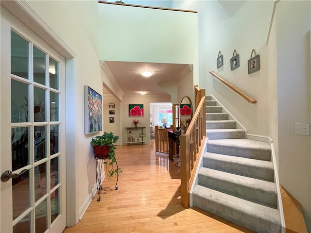 staircase with wood-type flooring and crown molding