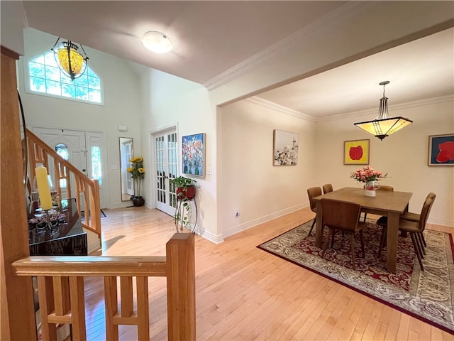 dining area featuring hardwood / wood-style flooring, ornamental molding, a high ceiling, and french doors