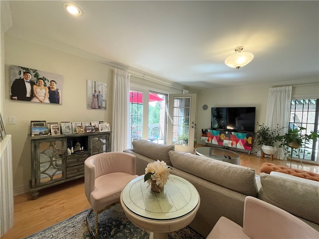 living room with light hardwood / wood-style flooring, a wealth of natural light, and ornamental molding