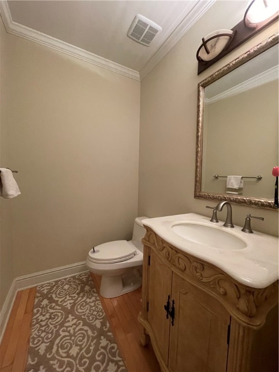 bathroom featuring vanity, toilet, wood-type flooring, and crown molding