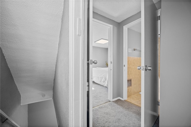 hallway featuring a textured ceiling and light colored carpet