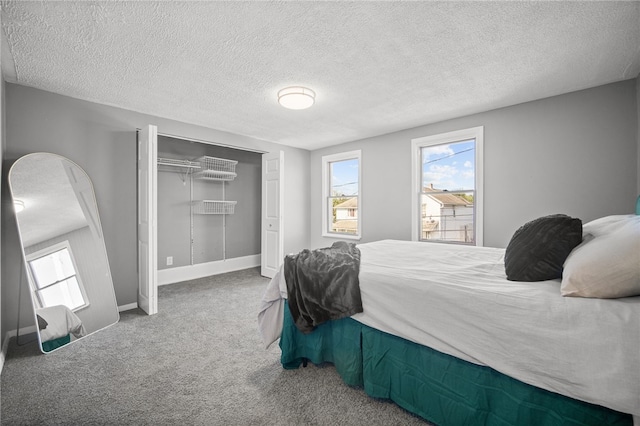 bedroom with a textured ceiling, carpet floors, and a closet