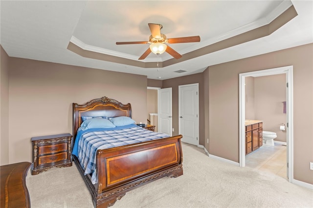 carpeted bedroom featuring ceiling fan, crown molding, a tray ceiling, and ensuite bath