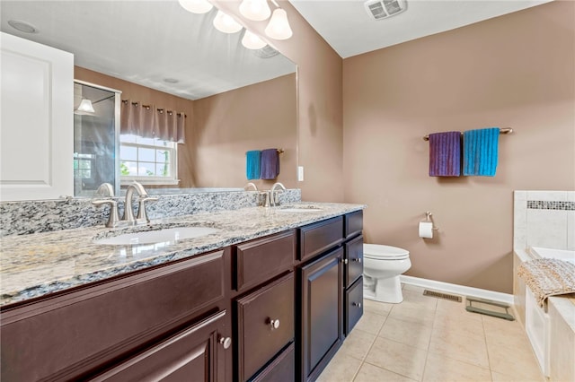 bathroom with tile patterned floors, dual vanity, a bath, and toilet