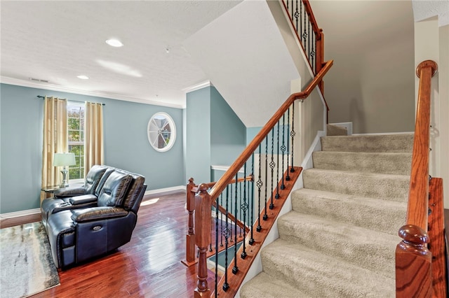 staircase featuring crown molding, wood-type flooring, and a textured ceiling