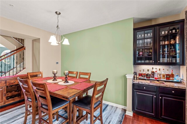 dining room with dark wood-type flooring and an inviting chandelier