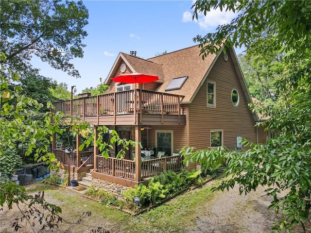 back of property featuring a deck and roof with shingles