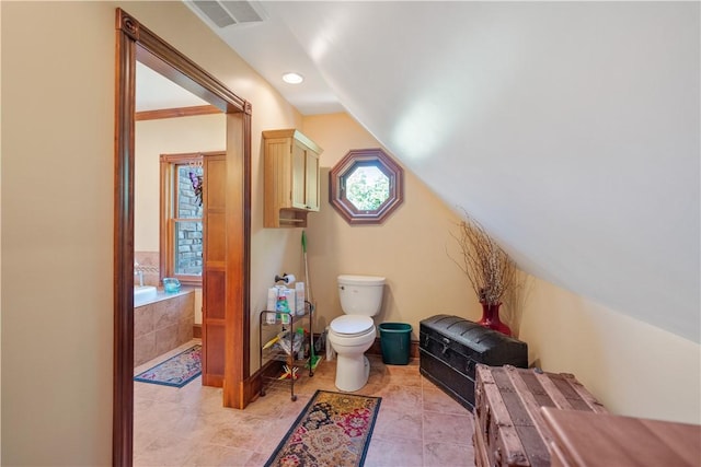 full bathroom featuring a bath, toilet, and vaulted ceiling