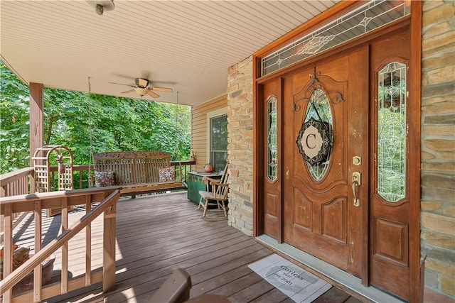 property entrance with stone siding, ceiling fan, and a porch