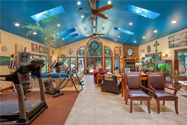 interior space featuring a skylight, a stone fireplace, light tile patterned flooring, and ceiling fan