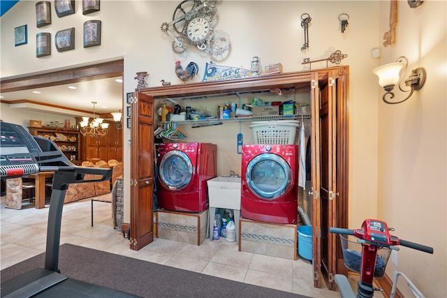 laundry room with light tile patterned flooring, washing machine and dryer, and an inviting chandelier