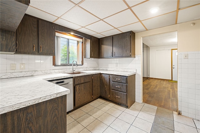 kitchen with stainless steel dishwasher, light hardwood / wood-style floors, sink, decorative backsplash, and dark brown cabinetry