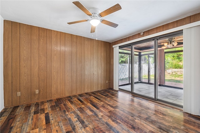 unfurnished room with ceiling fan, dark hardwood / wood-style flooring, and wooden walls