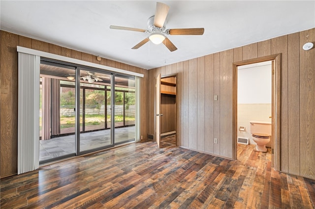 unfurnished room with ceiling fan, wooden walls, and hardwood / wood-style flooring