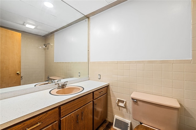 bathroom featuring vanity, tile walls, and toilet