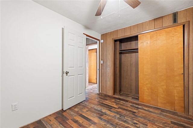 unfurnished bedroom with ceiling fan, dark wood-type flooring, and a closet