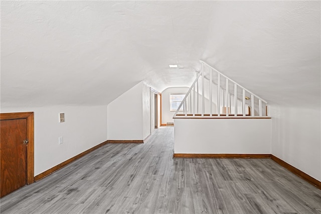 additional living space with vaulted ceiling and hardwood / wood-style flooring