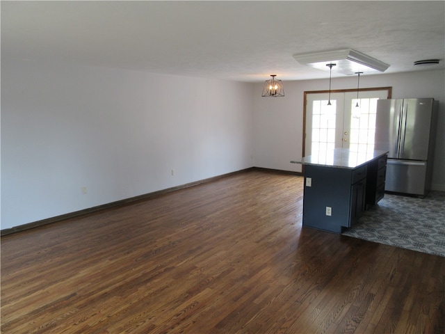 interior space with dark hardwood / wood-style flooring, decorative light fixtures, a kitchen island, and stainless steel refrigerator