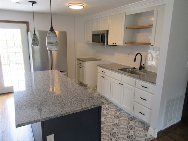 kitchen featuring light stone countertops, white cabinetry, backsplash, sink, and a kitchen island