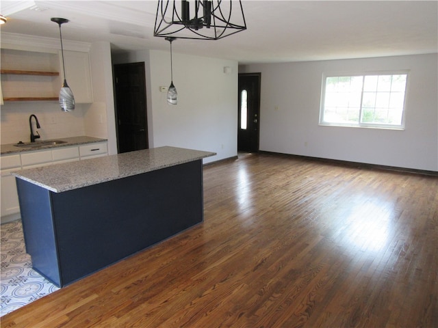 kitchen featuring sink, pendant lighting, hardwood / wood-style flooring, and white cabinetry