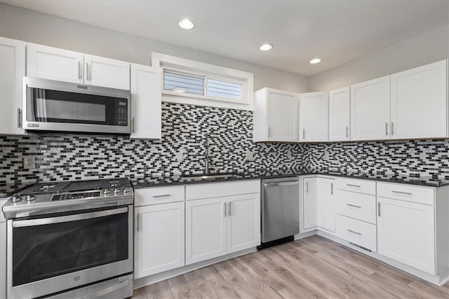 kitchen featuring dark countertops, light wood finished floors, stainless steel appliances, and decorative backsplash