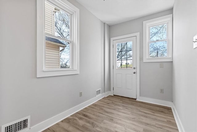 doorway to outside featuring visible vents, light wood-style flooring, and baseboards