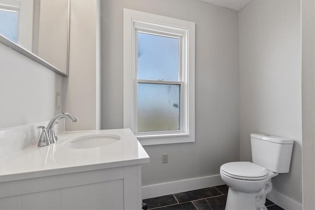 half bathroom featuring tile patterned flooring, toilet, vanity, and baseboards