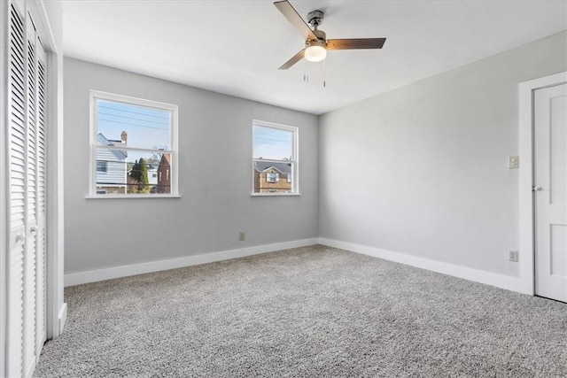 carpeted empty room featuring a ceiling fan and baseboards