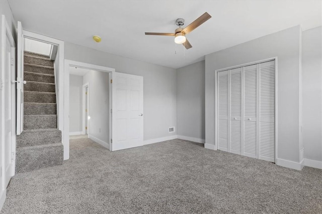 unfurnished bedroom with a ceiling fan, carpet, a closet, and baseboards