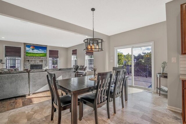 dining room featuring light tile patterned floors, a fireplace, and an inviting chandelier