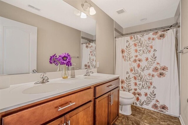 bathroom featuring dual vanity, toilet, and tile patterned flooring