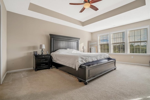 bedroom featuring light carpet, ceiling fan, and a raised ceiling