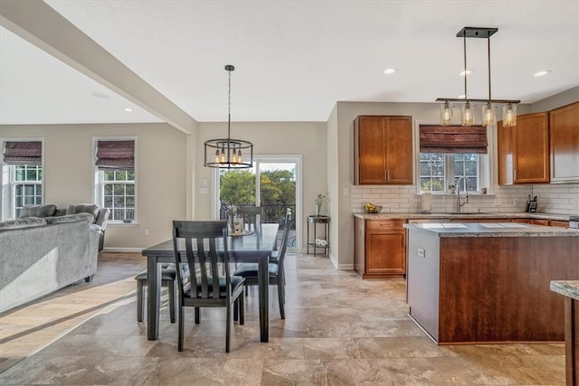 kitchen with light tile patterned floors, decorative backsplash, a healthy amount of sunlight, and decorative light fixtures