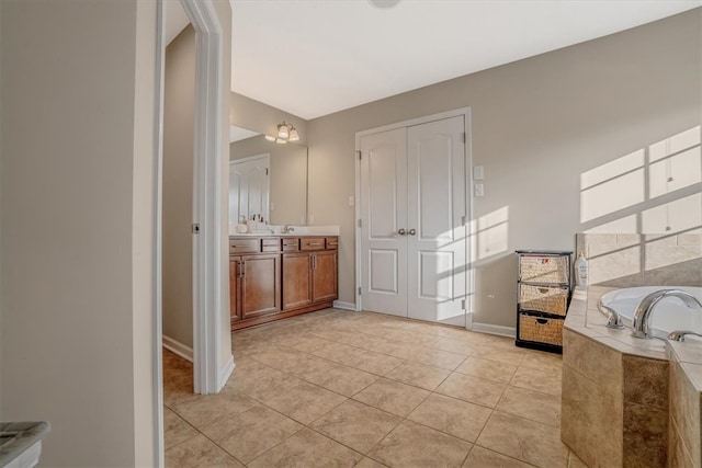 bathroom featuring a relaxing tiled tub, tile patterned flooring, and vanity