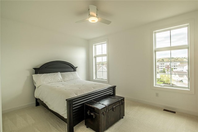 bedroom with a ceiling fan, light colored carpet, visible vents, and baseboards