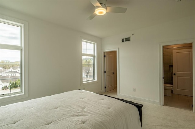 carpeted bedroom with ceiling fan, ensuite bathroom, visible vents, and baseboards