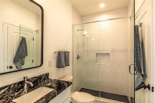 full bathroom featuring a shower stall, toilet, and vanity