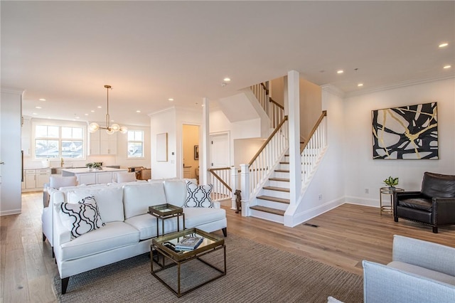 living area with light wood-style floors, recessed lighting, stairway, and ornamental molding