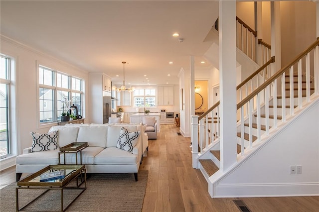 living area featuring visible vents, stairway, light wood-style floors, a notable chandelier, and recessed lighting