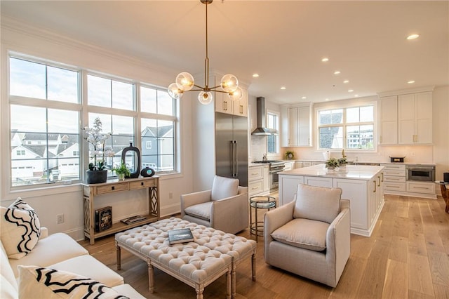 living area with light wood-style floors, recessed lighting, a notable chandelier, and baseboards