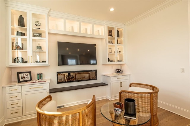 sitting room with light wood-style floors, recessed lighting, ornamental molding, and baseboards