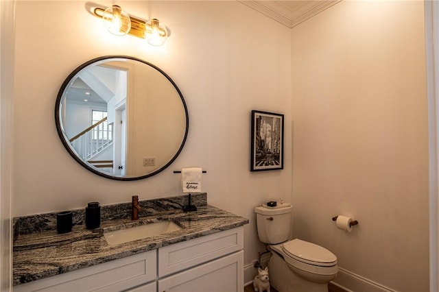 bathroom featuring crown molding, vanity, toilet, and baseboards