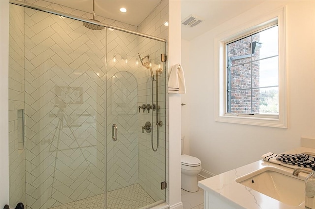 full bathroom featuring toilet, vanity, visible vents, baseboards, and a stall shower