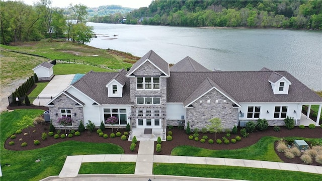 view of front of house with a water view, stone siding, and a front lawn