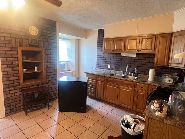 kitchen featuring a textured ceiling, light tile patterned floors, sink, and dark stone countertops